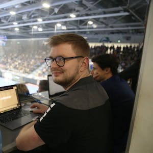 Jan Schwenzfeier sitzt während eines Handballspiels in der Schwalbe-Arena an einem Laptop.