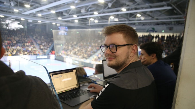 Jan Schwenzfeier sitzt während eines Handballspiels in der Schwalbe-Arena an einem Laptop.