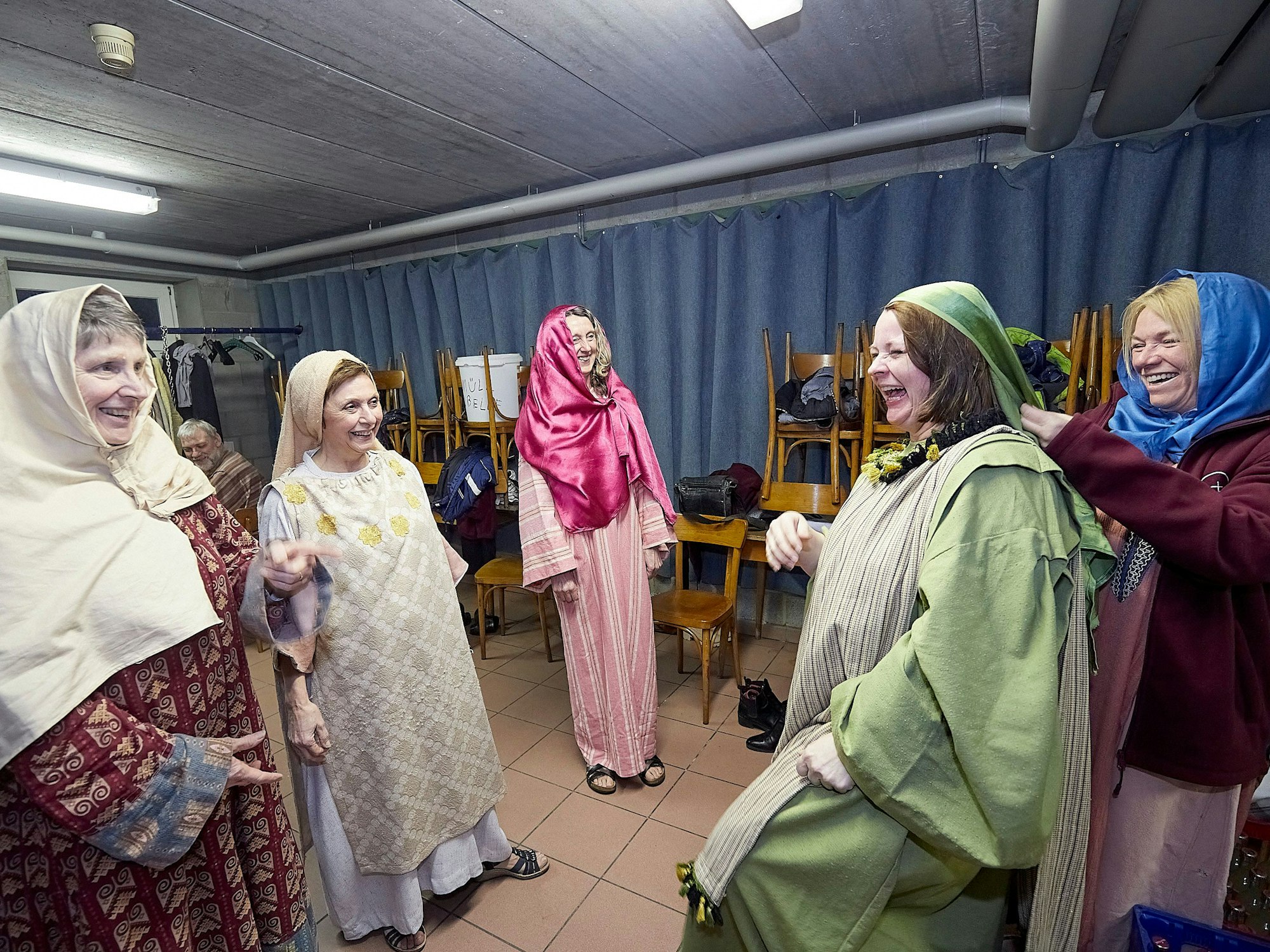 Fünf Frauen, die als Komparsen mitspielen, stehen lachend in ihrer Garderobe.