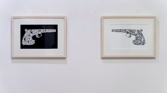 Zwei Bilder, die Pistolen zeigen, hängen an einer Wand.
