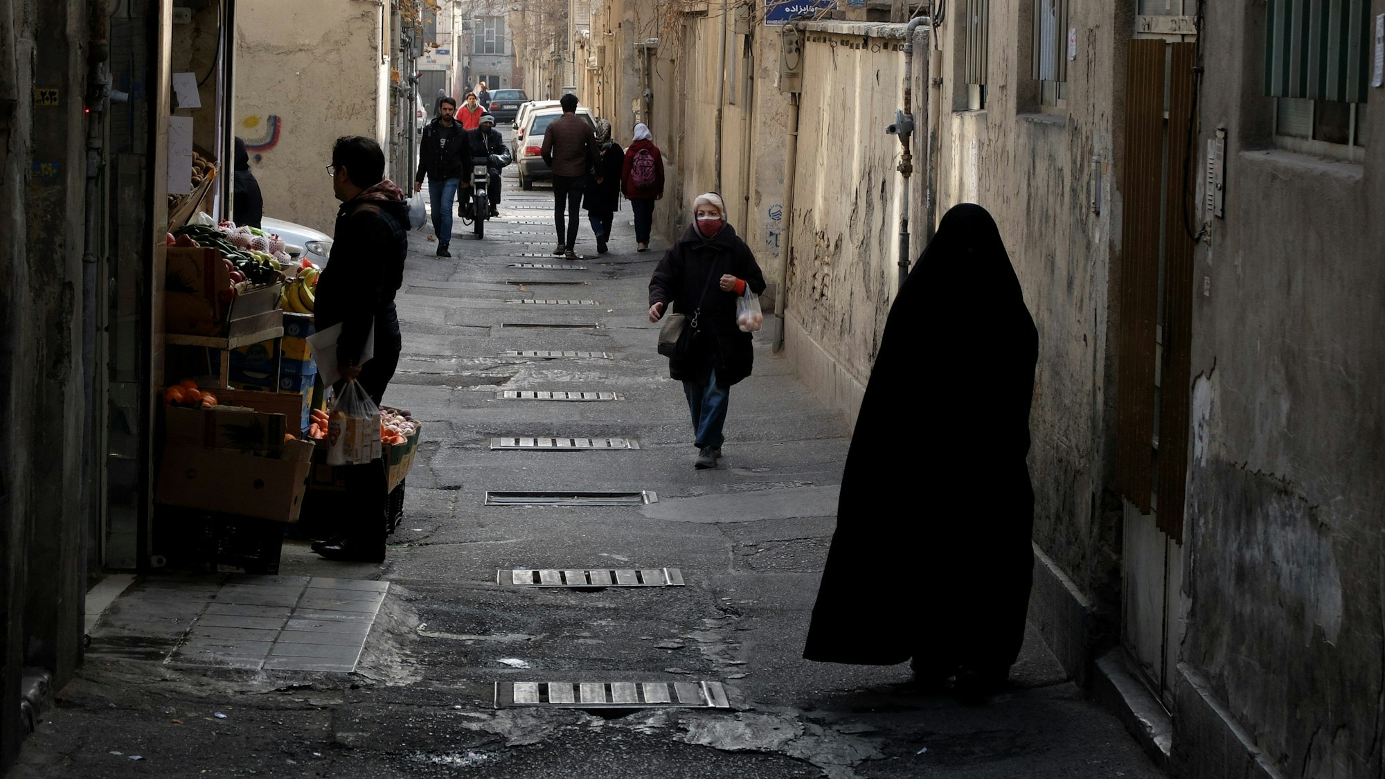 29.01.2023, Iran, Teheran: Menschen gehen im Stadtteil Shapour im Süden Teherans die Straße entlang.