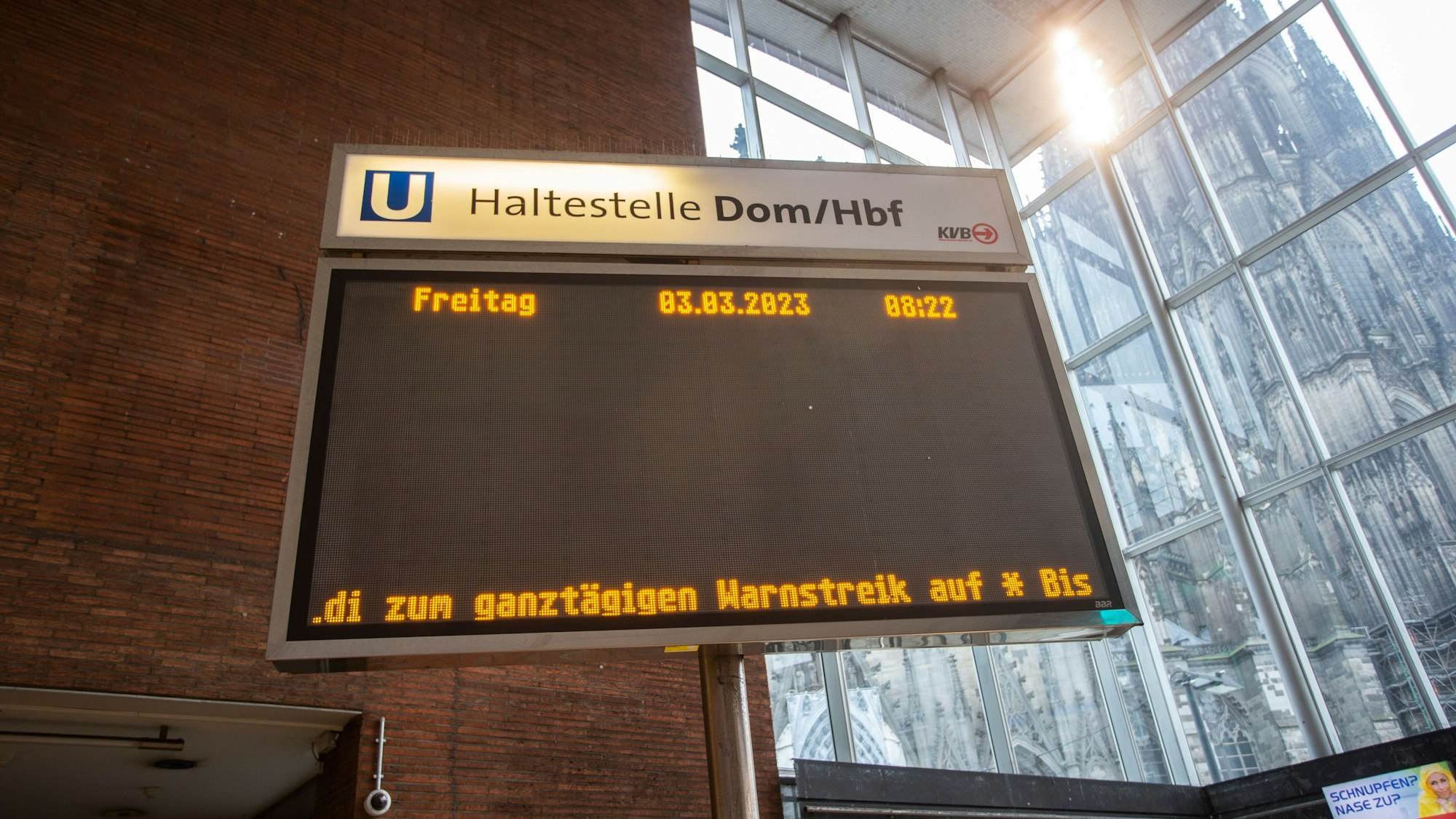 Über die Anzeigetafel am Dom Hauptbahnhof werden Reisende über den Streik informiert. Im Hintergrund ein Ausschnitt des Kölner Doms.