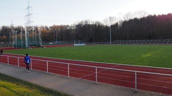 Ein Sportplatz mit roter Laufbahn und Wiese in der Mitte.