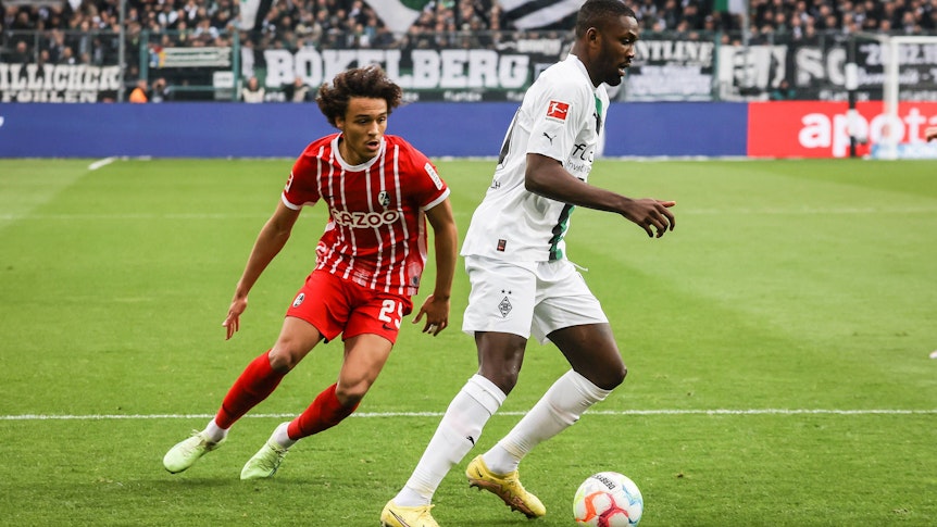 Borussia Mönchengladbach hat am Samstag (4. März 2023) 0:0 gegen den SC Freiburg gespielt. Das Foto zeigt SCF-Spieler Kiliann Sildillia (l.) im Laufduell mit Gladbachs Marcus Thuram (r.).