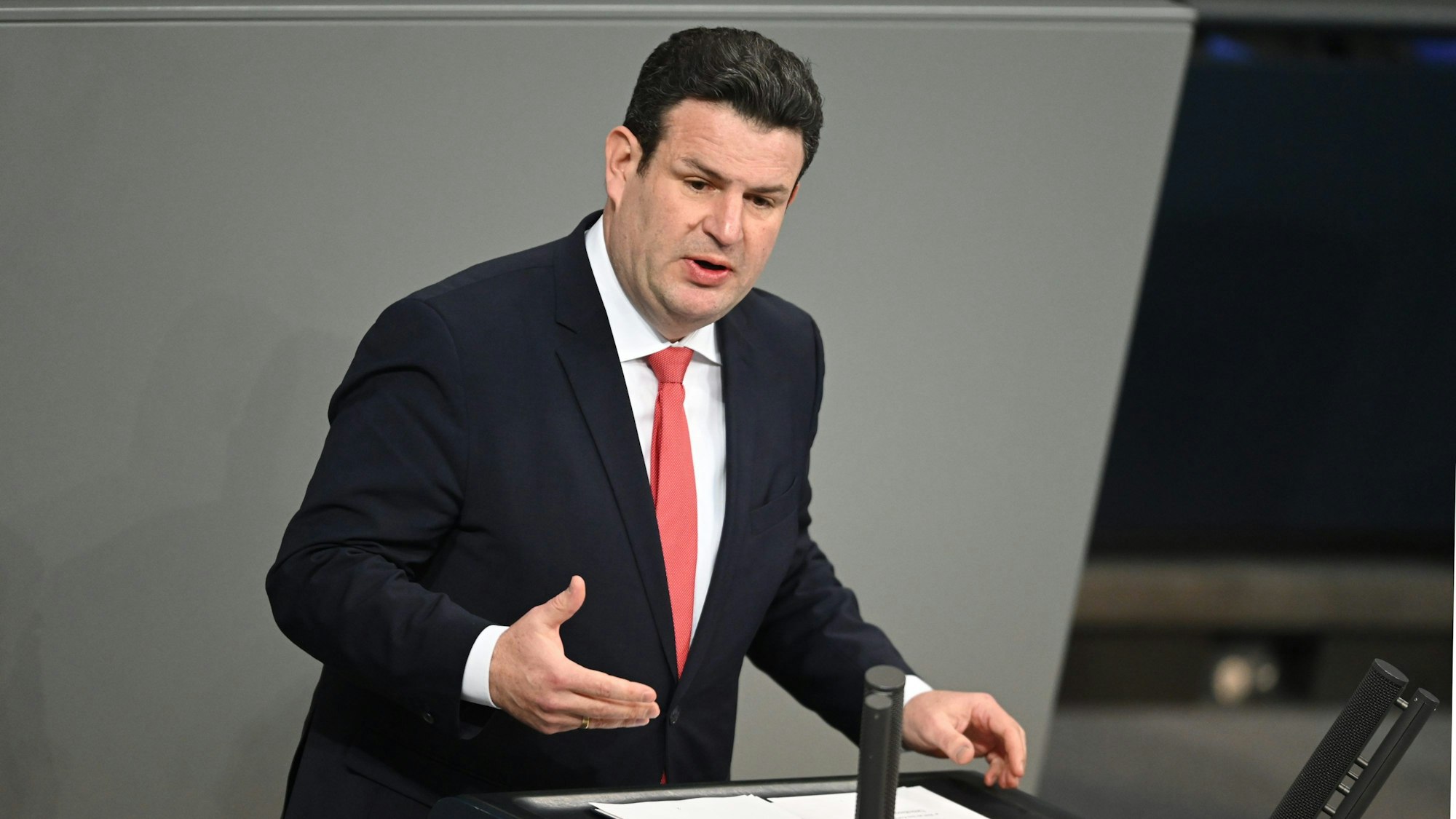 Hubertus Heil (SPD), Bundesminister für Arbeit und Soziales, spricht am Rednerpult im Plenum des Deutschen Bundestags. Er trägt einen schwarzen Anzug und rote Krawatte.