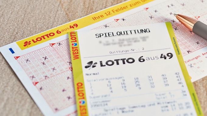 Ein Lotto 6aus49 Tippschein und ein Los liegen auf dem Tisch.