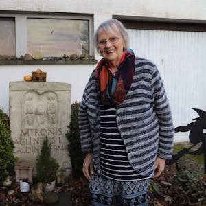 Sophie Lange neben einem Matronen-Stein, hinter ihr ein Haus.