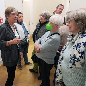 Die Künstlerin Gerda Laufenberg steht links und spricht angeregt mit Besuchern.
