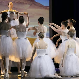 Mehrere Balletttänzerinnen tanzen auf der Bühne. Sie heben eine Tänzerin in ihrer Mitte hoch.&nbsp;
