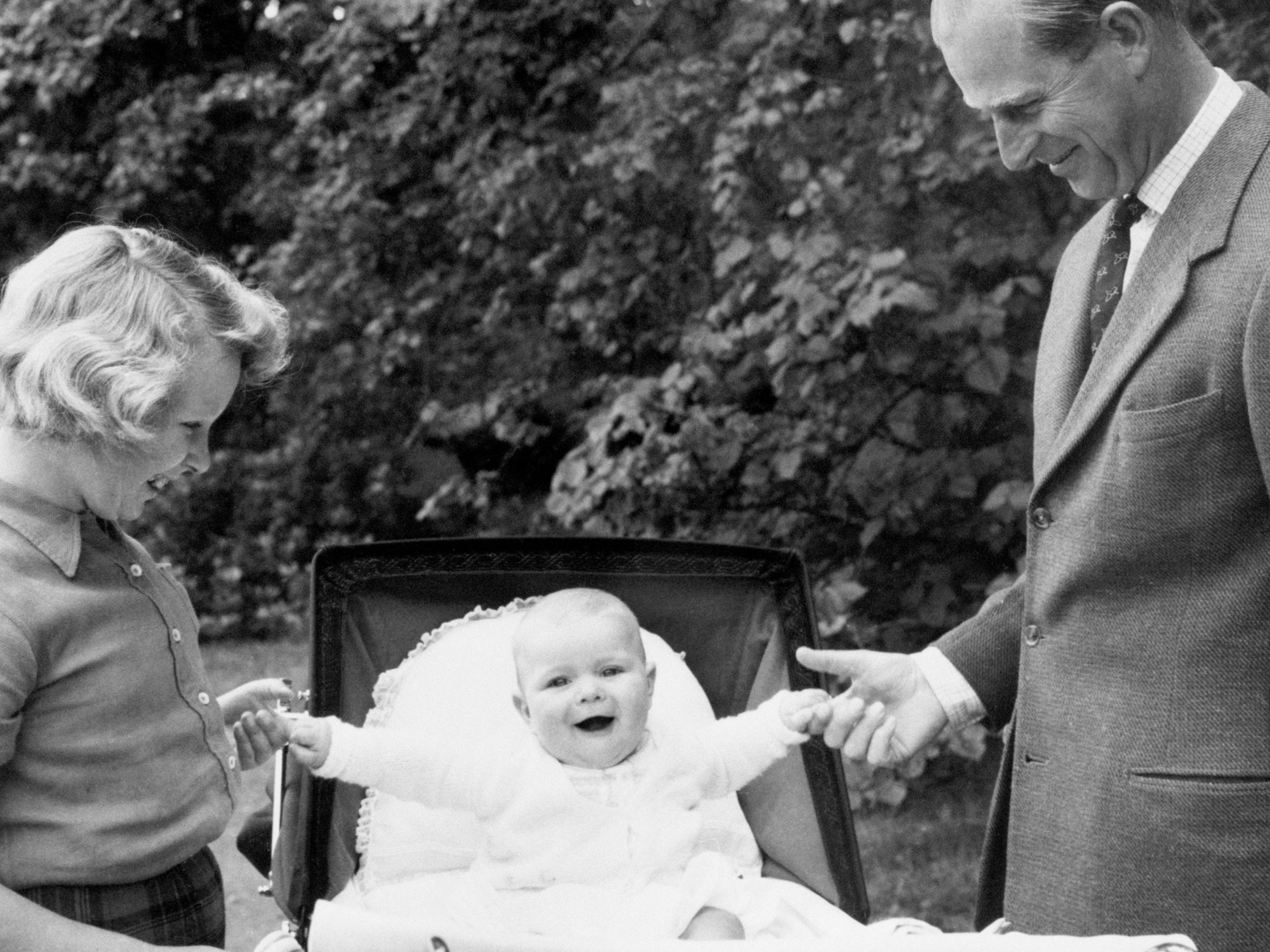 Der britische Prinz Philip und Prinzessin Anne halten die Hände von Prinz Andrew, der in einem Kinderwagen sitzt.