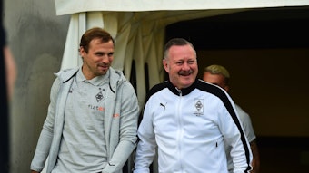 Tony Jantschke (l.) und Roland Virkus von Borussia Mönchengladbach betreten am 1. Juli 2022 den Innenraum im Stadion an der Hafenstraße vor dem Testspiel bei Rot-Weiss Essen. Beide sprechen miteinander und grinsen.