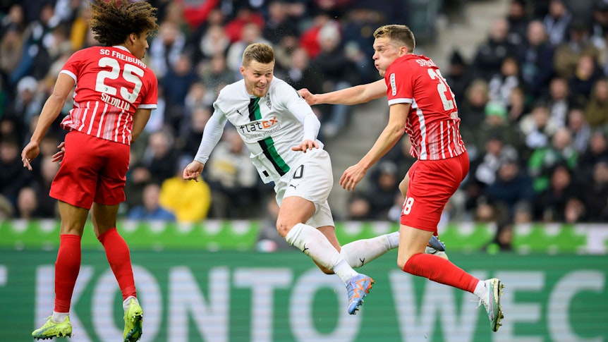 Nico Elvedi (M.) geht im Spiel von Borussia Mönchengladbach gegen den SC Freiburg am 4. März 2023 in ein Kopfball-Duell mit seinem Ex-Teamkollegen Matthias Ginter (r.) und köpft den Ball in Richtung des Freiburg-Tores. Auch Kiliann Sildillia springt dem Ball entgegen.