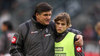 Trainer Hans Meyer (l.) spricht vor dem Bundesliga-Spiel von Borussia Mönchengladbach gegen Bayer Leverkusen am 6. Dezember 2008 mit Startelf-Debütant Tony Jantschke. Der Trainer legt beim Aufwärmen im Borussia-Park seinen Arm um den Teenager.
