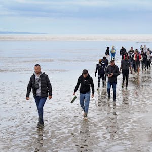 Eine Gruppe von Menschen, bei denen es sich vermutlich um Migranten handelt, geht an Land, nachdem sie nach einem Zwischenfall mit einem kleinen Boot im Ärmelkanal vom Rettungsboot ‚Dungeness‘ abgefangen wurde.