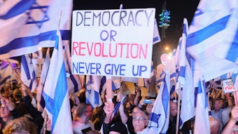 Israelische Bürger demonstrieren in der nordisraelischen Stadt Karmiel gegen die Justizreform ihrer Regierung. Die Demonstrierenden schwenken israelische Flaggen. Auf einem hochgehaltenen Plakat steht: „Democracy or Revolution. Never gib up“ - Demokratie oder Revolution. Niemals aufgeben!