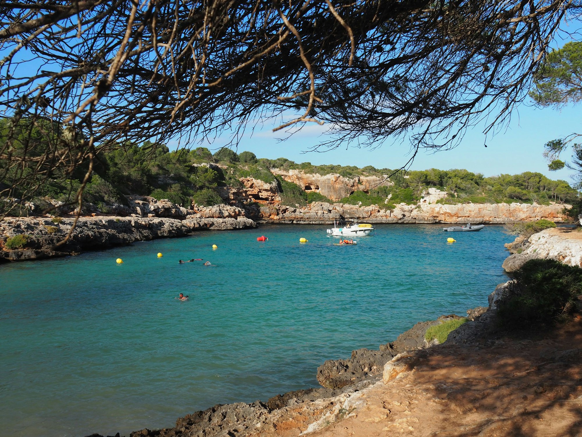 Die Bucht von Cala Sa Nau auf Mallorca, hier im Juli 2020, mit schwimmenden Menschen, Bojen und Booten im Wasser.
