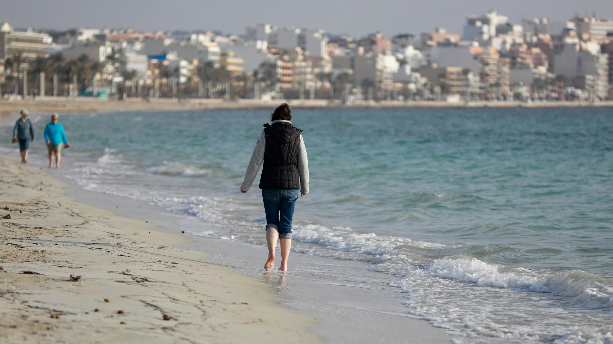 Touristen laufen am Strand von Arenal auf Mallorca.