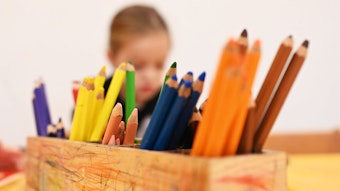Ein Kind malt in einer Kita mit Buntstiften.