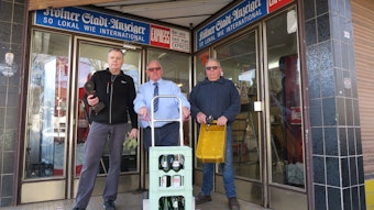Hans-Joachim Grebe, Gottfried Schneider und Klaus Bensch stehen vor dem Laden mit einer Sackkarre.
