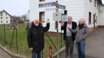 Elke Schomers, Peter Klippelt und Herbert Daniels stehen unter einem Straßenschild.