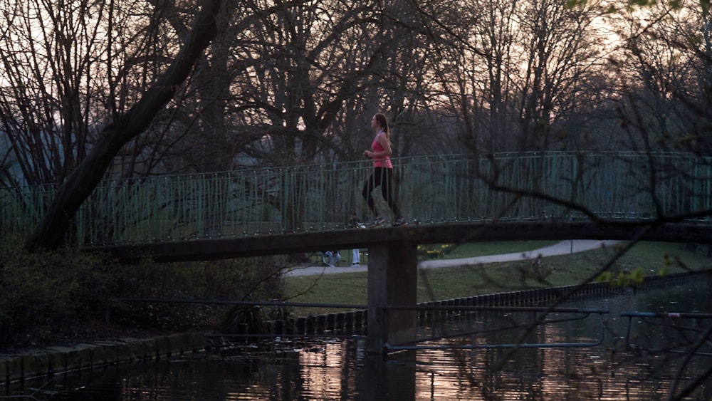 Frau läuft im Kölner Stadtwald über eine Brücke am Kahnweiher.