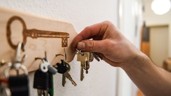 Ein Mann hängt einen Schlüsselbund an einen Haken am Schlüsselbrett an.