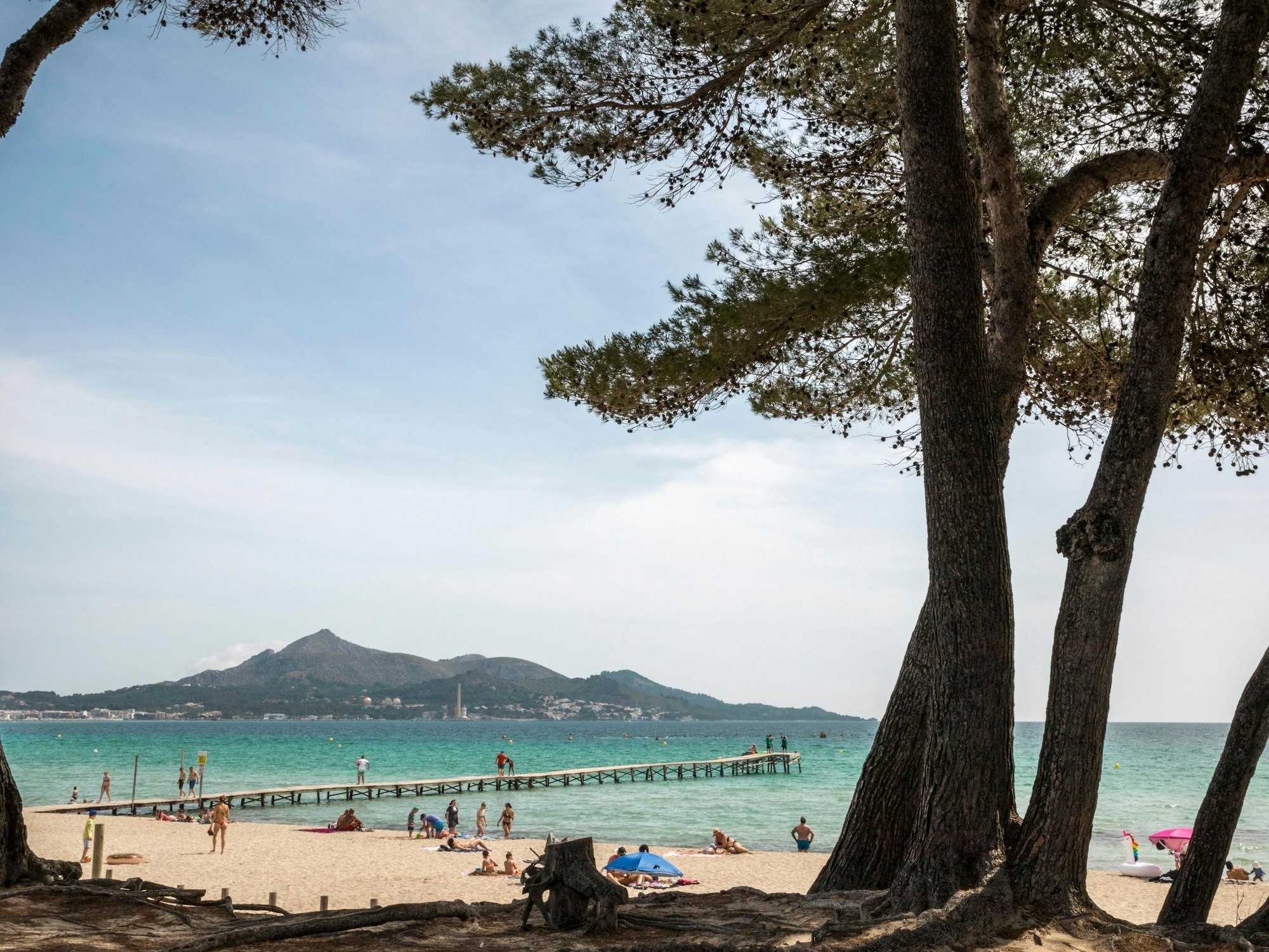 Menschen genießen das schöne Wetter am Strand von Muro auf Mallorca.