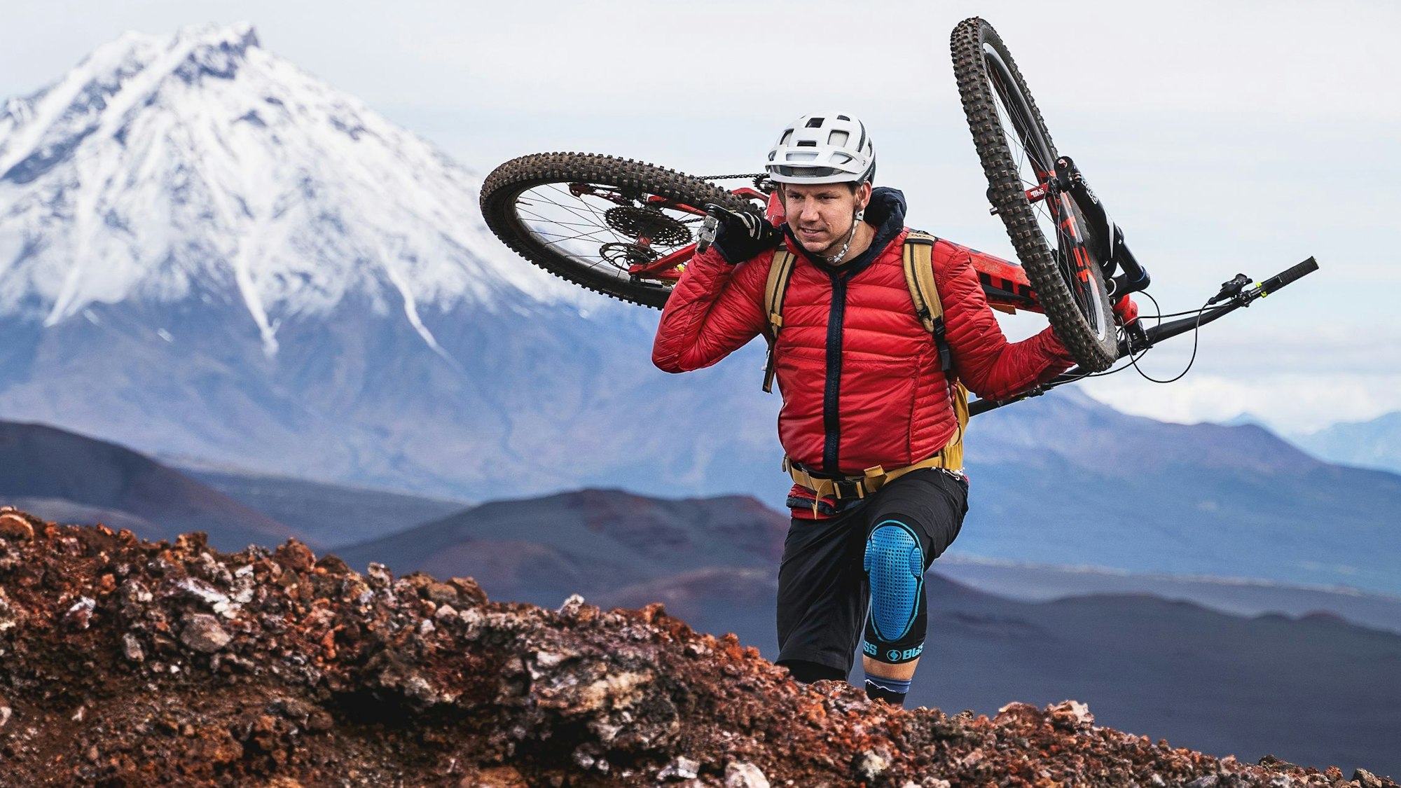 Tobias Woggon trägt sein Mountainbike einen Berg hinauf.