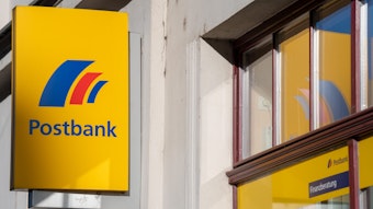 Brandenburg an der Havel: Ein Schild mit dem Logo der Postbank ist an der Fassade einer Bankfiliale angebracht.