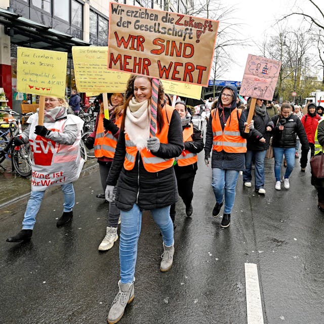 Eine Demonstrantin trägt ein Schild mit der Aufschrift "Wir erziehen die Zukunft der Gesellschaft. Wir sind mehr wert!" auf einer Demo für mehr Lohn in Sozialberufen in Köln.&nbsp;