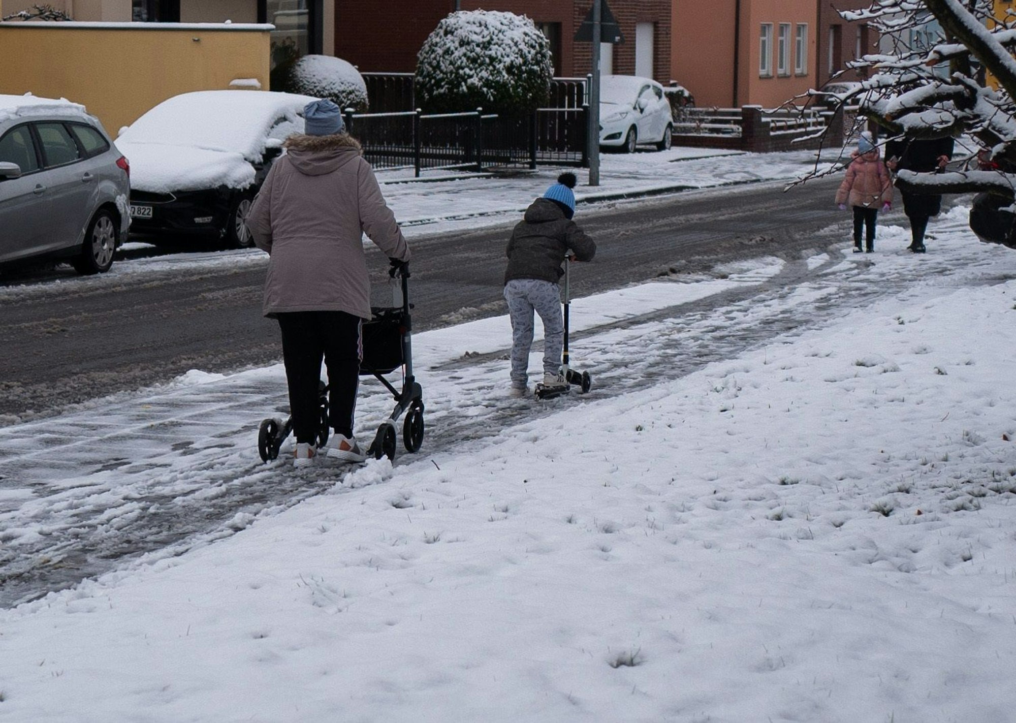 Mehrere Personen gehen über eine mit Schnee bedeckte Straße