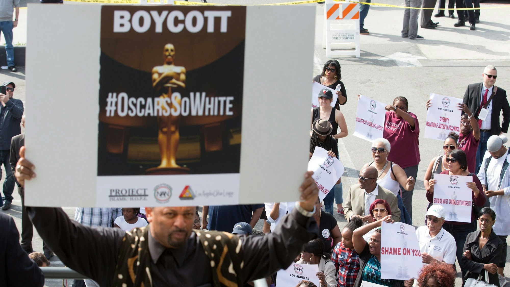 Ein Demonstrant hält ein Plakat mit der Aufschrift „Boycott“ und „#OscarsSoWhite“ während einer Demonstration gegen die Nominierung vorwiegend weißer Schauspielerinnen und Schauspieler für die Oscars 2016 hoch.