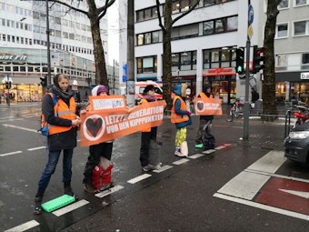 Am Zülpicher Platz in Köln stehen Demonstrierende der „Letzten Generation“ auf der Straße.