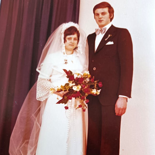 Gerda (l.) im Brautkleid und Peter im Anzug mit rosa Fliege.