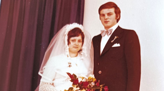 Gerda (l.) im Brautkleid und Peter im Anzug mit rosa Fliege.