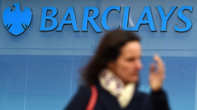 Das Symbolfoto von 2016 zeigt eine Glasfassade mit dem blauen Schriftzug „Barclays“ und einem stilisierten Adler links daneben. Im Vordergrund des Fotos ist eine Frau zu sehen.