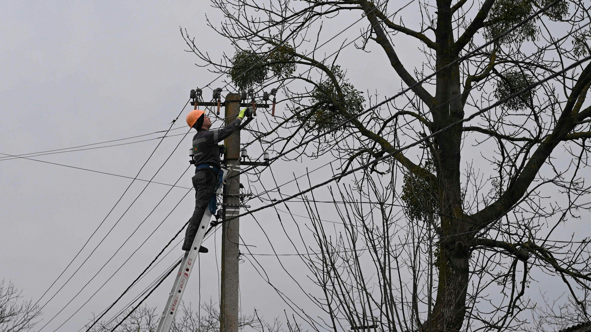 Ein Arbeiter repariert nach einem russischen Angriff eine Stromleitung in einem Dorf in der Nähe der ukrainischen Stadt Lwiw.