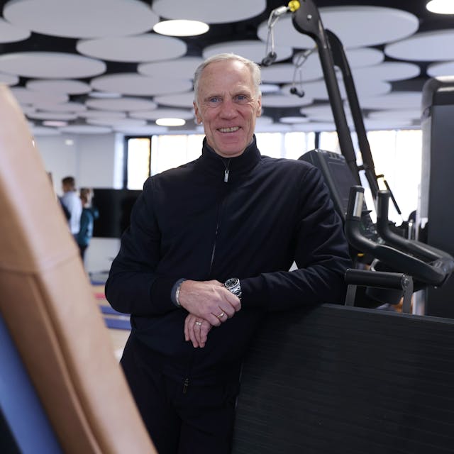 Ingo Froböse lehnt an einem Fitnessgerät in einem Fitnessstudio.
