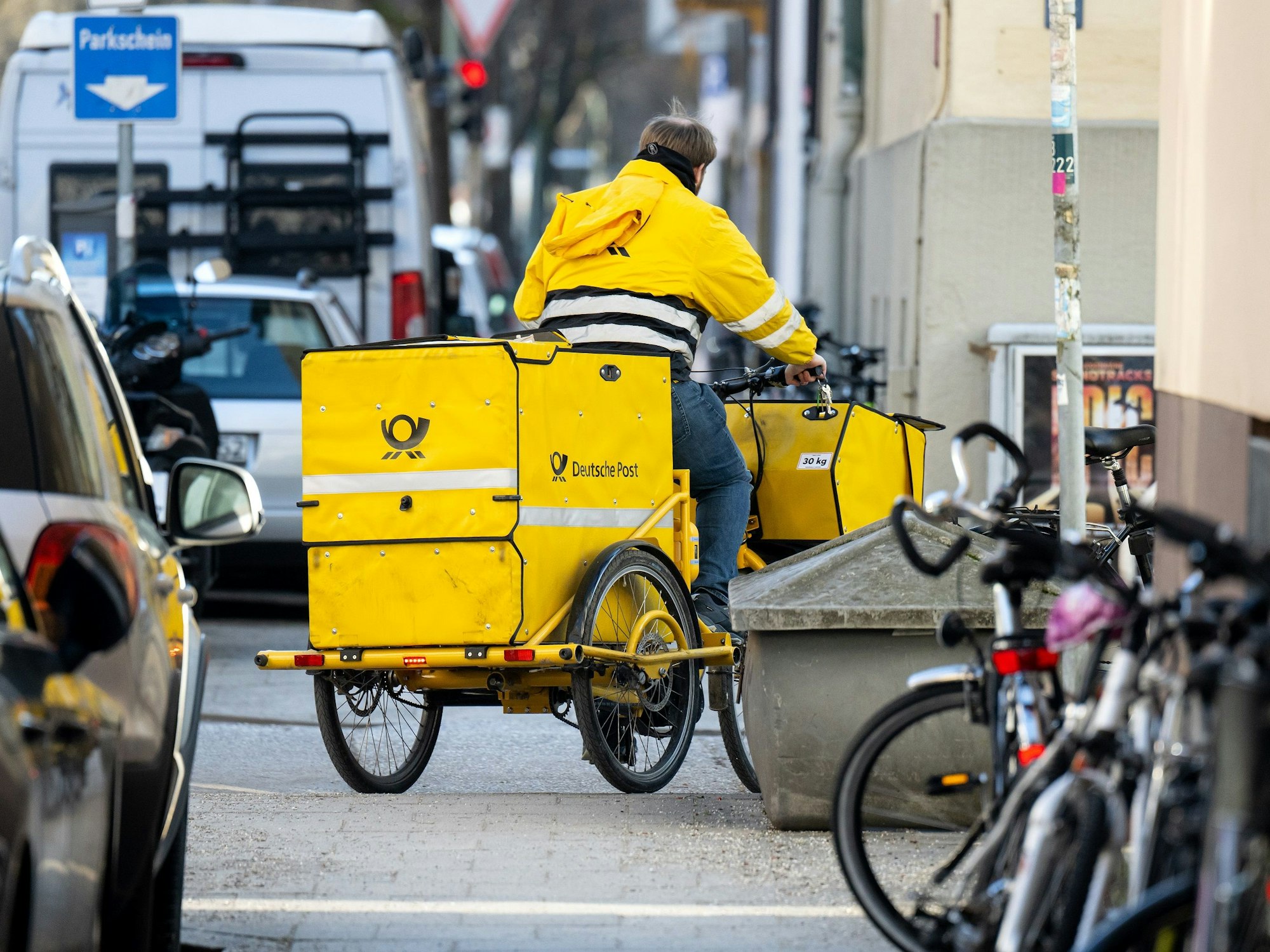 Ein Briefträger fährt mit seinem Fahrrad eine Straße in München entlang. Bei der Deutschen Post gehen die Verhandlungen zwischen Arbeitgebern und Verdi nach einem klaren Streik-Votum an diesem Freitag weiter.