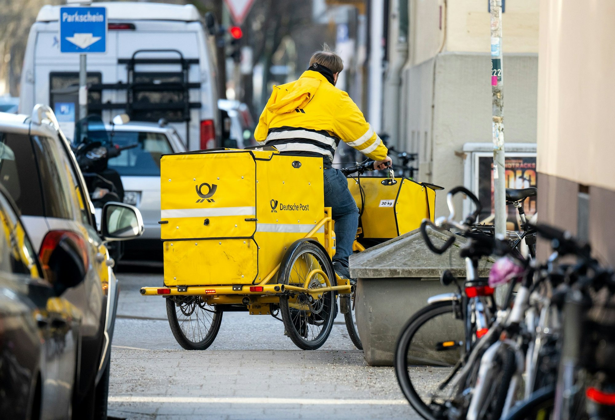 Das undatierte Foto zeigt einen Mitarbeiter der Deutschen Post. Er trägt Briefe mit einem gelben Lastenfahrrad aus.