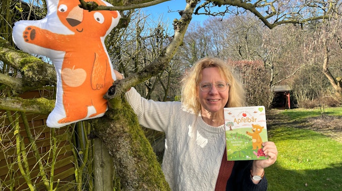 Ein aufblasbarer Apfelbär sitzt im Apfelbaum, Annette Langen mit ihrem Buch
