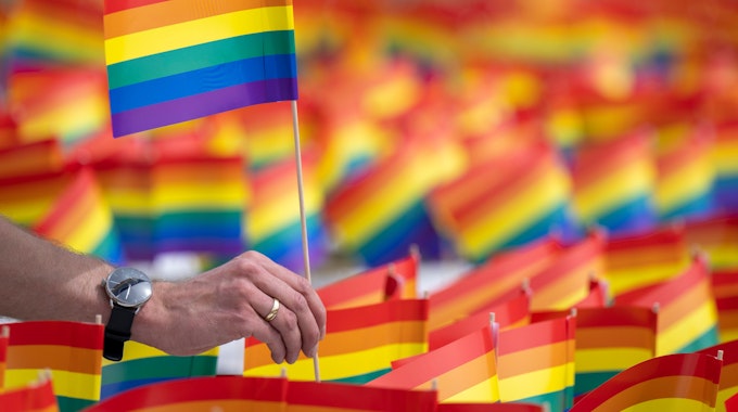Eine Person hält eine kleine Regenbogen-Flagge, das zeichen der Pride-Bewegung. (Symbolbild)