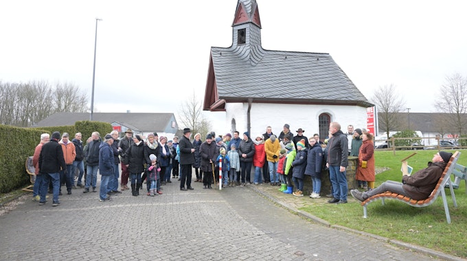 Menschen stehen bei der Eröffnung des Schöpfungswanderweg in Bechen vor einer Kirche.