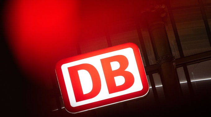 Das Logo der Deutschen Bahn leuchtet am Hauptbahnhof hinter einer Ampel.