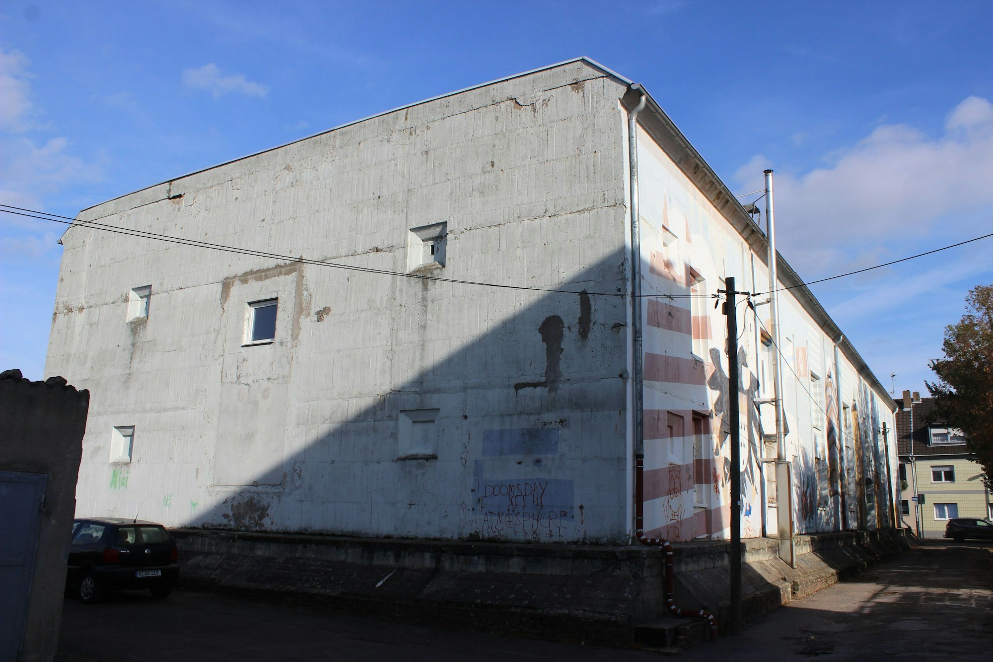 Ein teilweise mit Graffiti besprühter weißer Betonklotz steht an einer Straße.