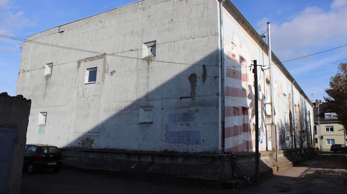 Ein teilweise mit Graffiti besprühter weißer Betonklotz steht an einer Straße.