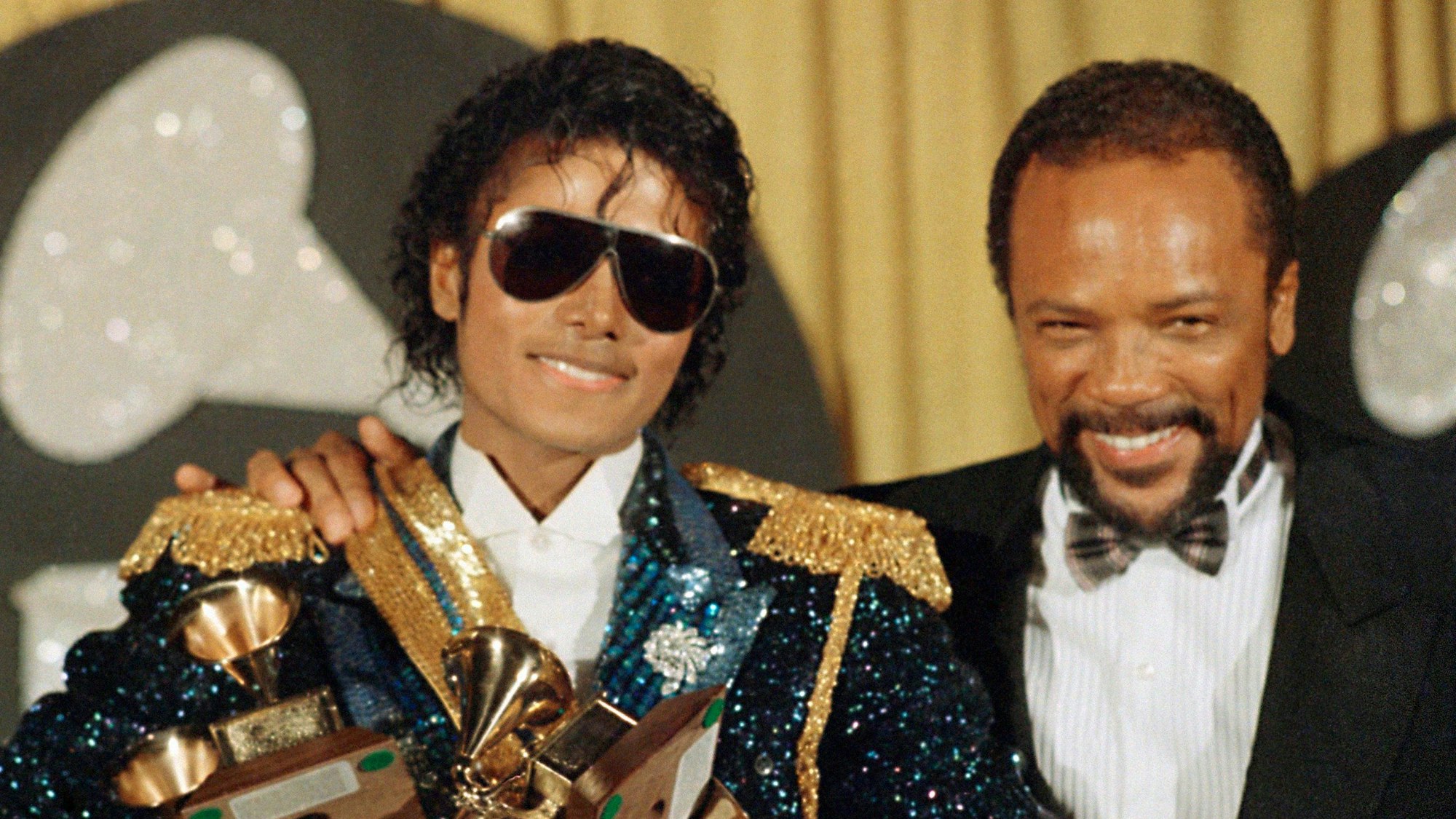 US-Popstar Michael Jackson (l) und US-Musikproduzent Quincy Jones stehen mit Grammy-Trophäen bei der Verleihung der Grammy Awards im Jahr 1984 nebeneinander. Jones wird am 14. März 2023 90 Jahre alt. (zu dpa-Porträt Der Alleskönner der Musik-Industrie: Quincy Jones wird 90) Foto: Doug Pizac/AP/dpa +++ dpa-Bildfunk +++