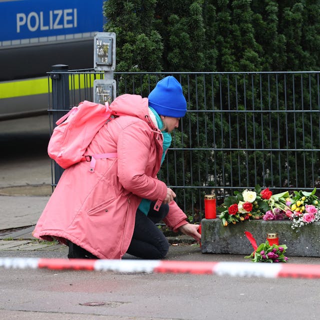 Eine Frau legt vor dem Gebäude der Zeugen Jehovas im Stadtteil Alsterdorf Blumen nieder.
