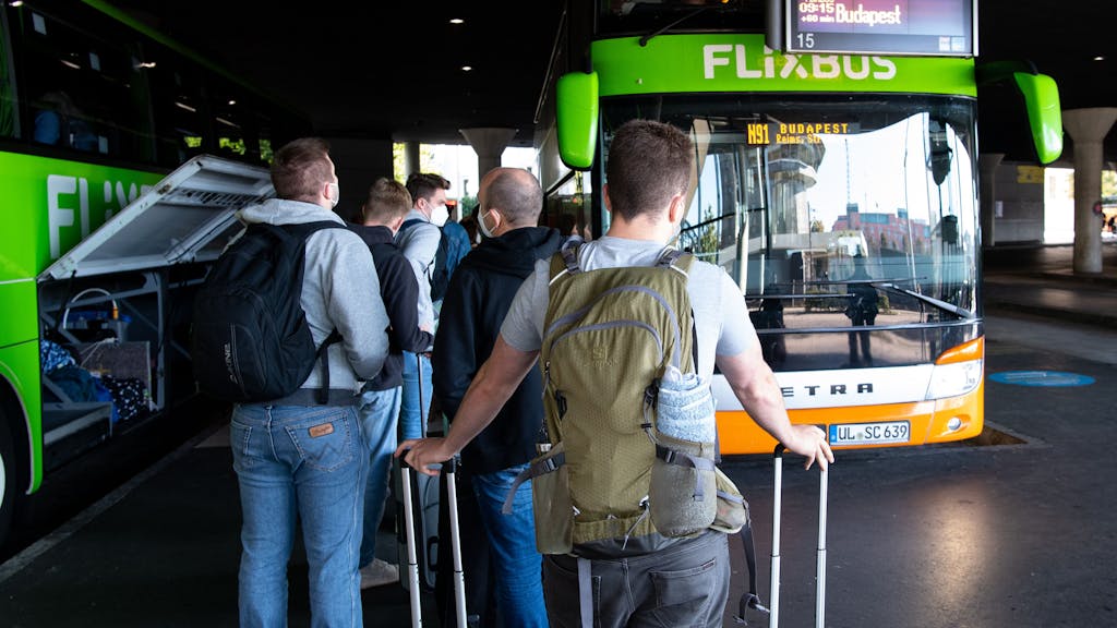 Reisende stehen im Jahr 2021 am Busbahnhof (ZOB) in München an einem Flixbus.