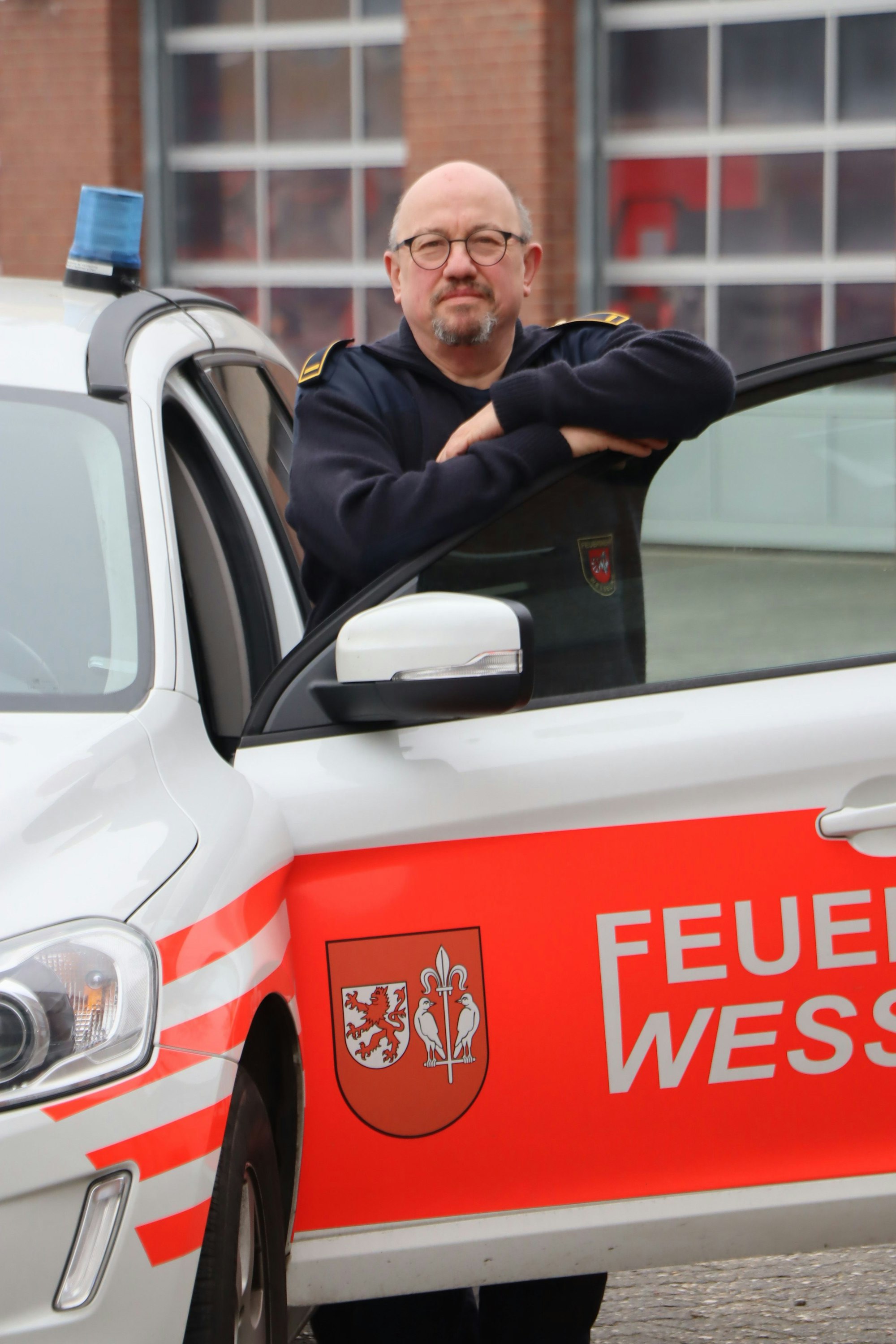 Wesselinger Feuerwehrchef André Bach sütztz sich mit beiden Armen auf der offenen Tür eines Feuerwehrautos.